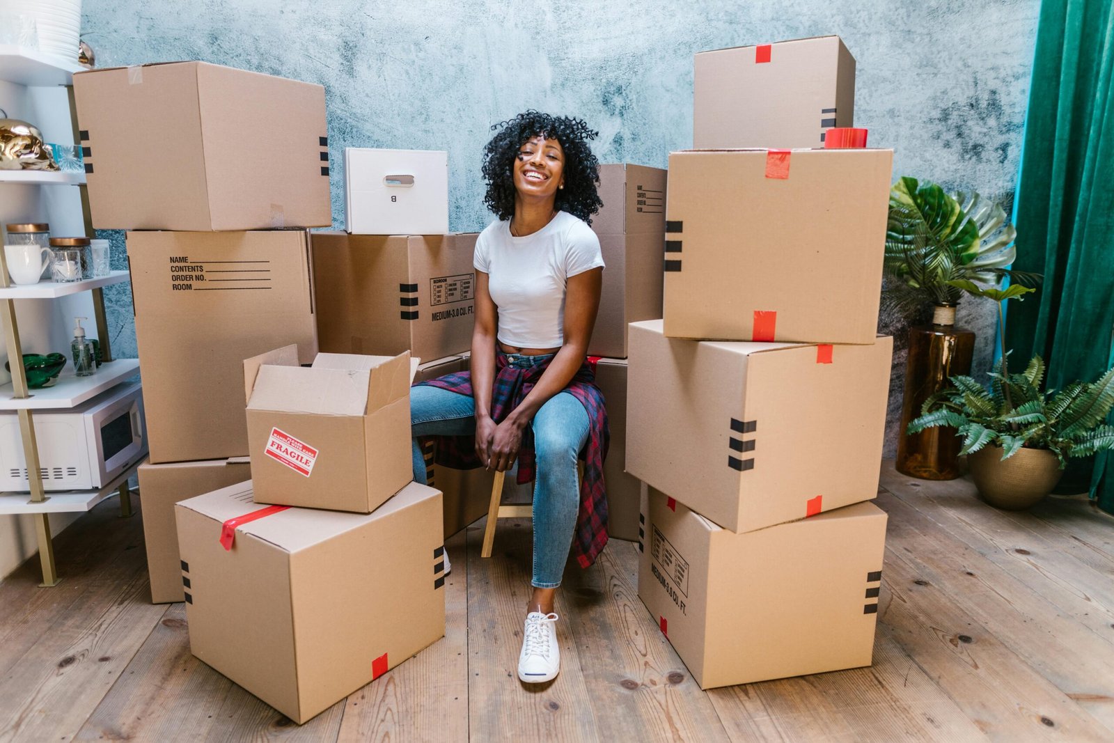 African American woman sitting among cardboard boxes, preparing for a move.